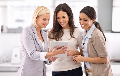 Buy stock photo Cropped shot of three businesswoman looking at a tablet in the office