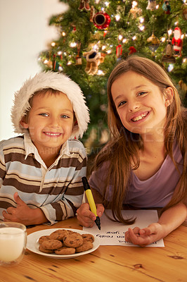 Buy stock photo Christmas portrait, girl and boy writing letter to Santa with milk glass, cookies and tree in home. Kids, smile and holiday with message on paper at table for Father Christmas, celebration and gift