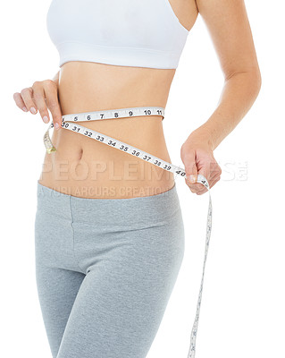 Buy stock photo Cropped studio shot of a woman measuring her waist with a measuring tape -Isolated image