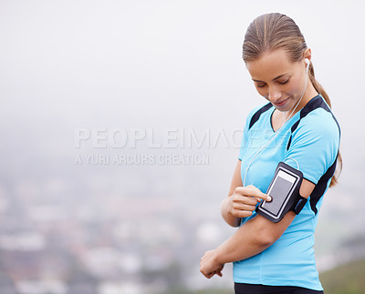 Buy stock photo Shot a young woman training outdoors while using a smartphone to monitor her progress
