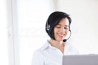 Buy stock photo Shot of an attractive young woman wearing a headset while using her laptop