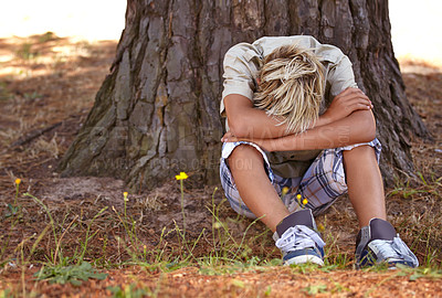 Buy stock photo Sad boy, stress and depression by tree with anxiety, mental health or bored on grass in nature. Male person, child or teenager resting head on arms by stump in loneliness, childhood or left out