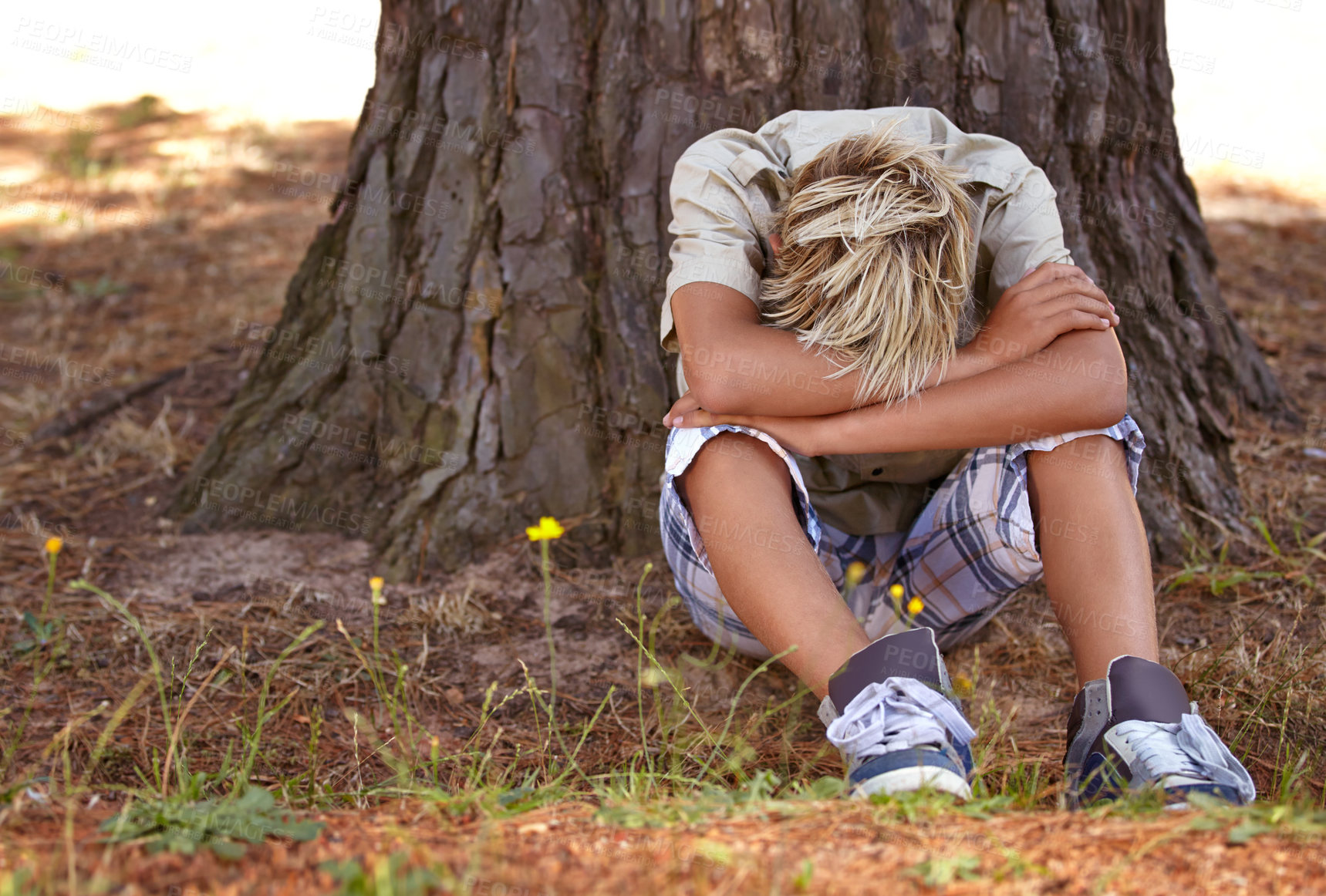 Buy stock photo Sad boy, stress and depression by tree with anxiety, mental health or bored on grass in nature. Male person, child or teenager resting head on arms by stump in loneliness, childhood or left out