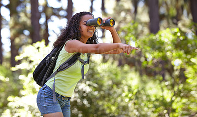 Buy stock photo Happy girl, binoculars and pointing in nature with backpack for sightseeing, explore or outdoor vision. Young female person, child or teenager enjoying adventure, bird watching or search in forest