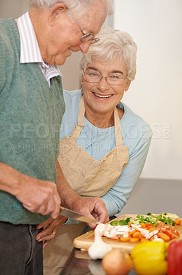 Buy stock photo Senior couple, cutting vegetables and cooking together in kitchen, food preparation and love at home. Elderly people, healthy meal and organic ingredients for nutrition, conversation and retirement