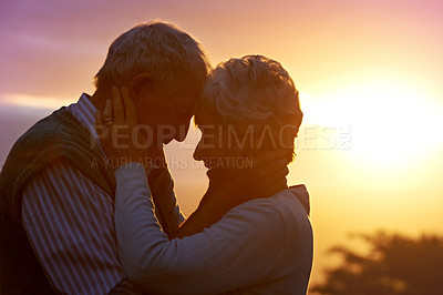 Buy stock photo Cropped shot of an elderly couple sharing a romantic moment at sunset
