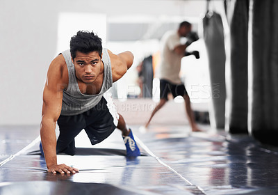 Buy stock photo Portrait of a focused young boxer doing push-ups in the gym