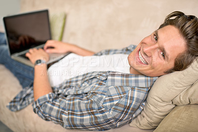 Buy stock photo Man, portrait and laptop on sofa or relax for online browsing at home or streaming movie, internet or scrolling. Male person, face and couch at house in London for weekend, resting or entertainment