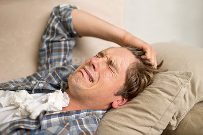 Buy stock photo A young man crying while lying on the sofa with tissues