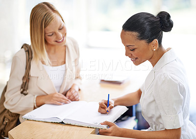 Buy stock photo Woman signing in with a receptionist at a desk for an appointment, meeting or reservation. Happy, conversation and secretary writing in a book for checking in at counter with female person in office.