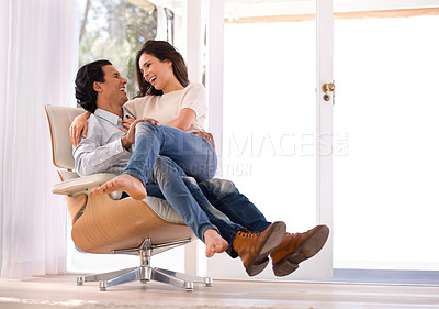 Buy stock photo Laughing, conversation and couple on chair in living room at home with comfortable romance and care. Happy, marriage and young man and woman sitting, talking and bonding together in lounge at house.