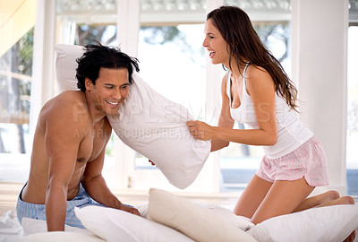Buy stock photo Happy, couple and pillow fight in bedroom for love affection and morning romance. Husband, wife and smiling in hotel room for joyful, laughter and marriage fun in pajamas for playing games and house