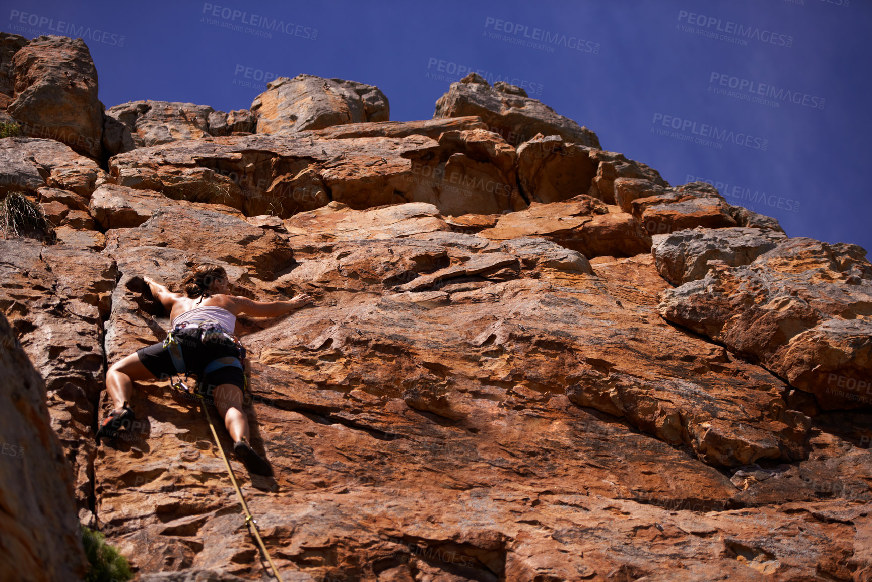 Buy stock photo Female person, rock climbing and outdoors for adventure, fitness and exercise in the sun for extreme sports. Woman, low angle and nature for wellness, mountain and fearless activity for strength 