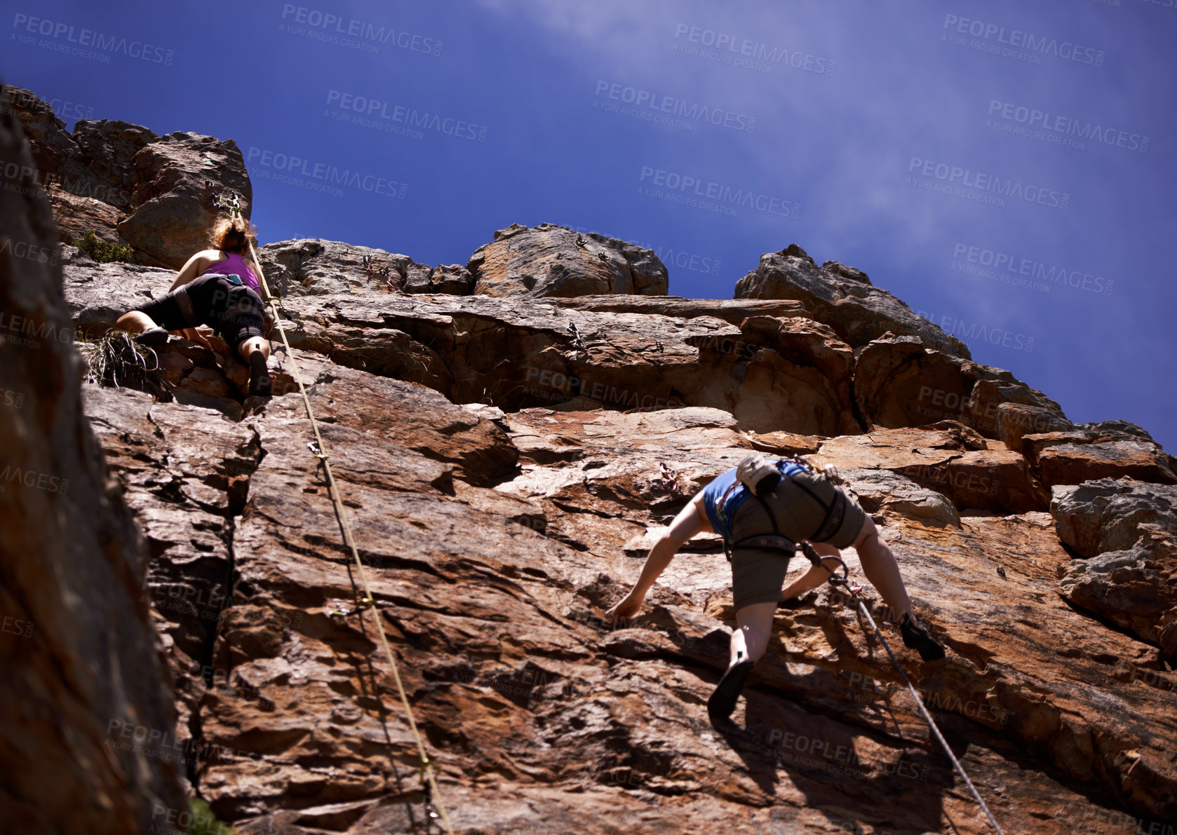 Buy stock photo Hikers, rock climbing and outdoors for adventure, fitness and exercise in the sun for extreme sports. People, climb wall and nature for wellness, mountain and fearless activity for strength 