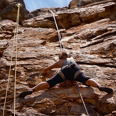 Buy stock photo Shot of a young female climber traversing a rock face