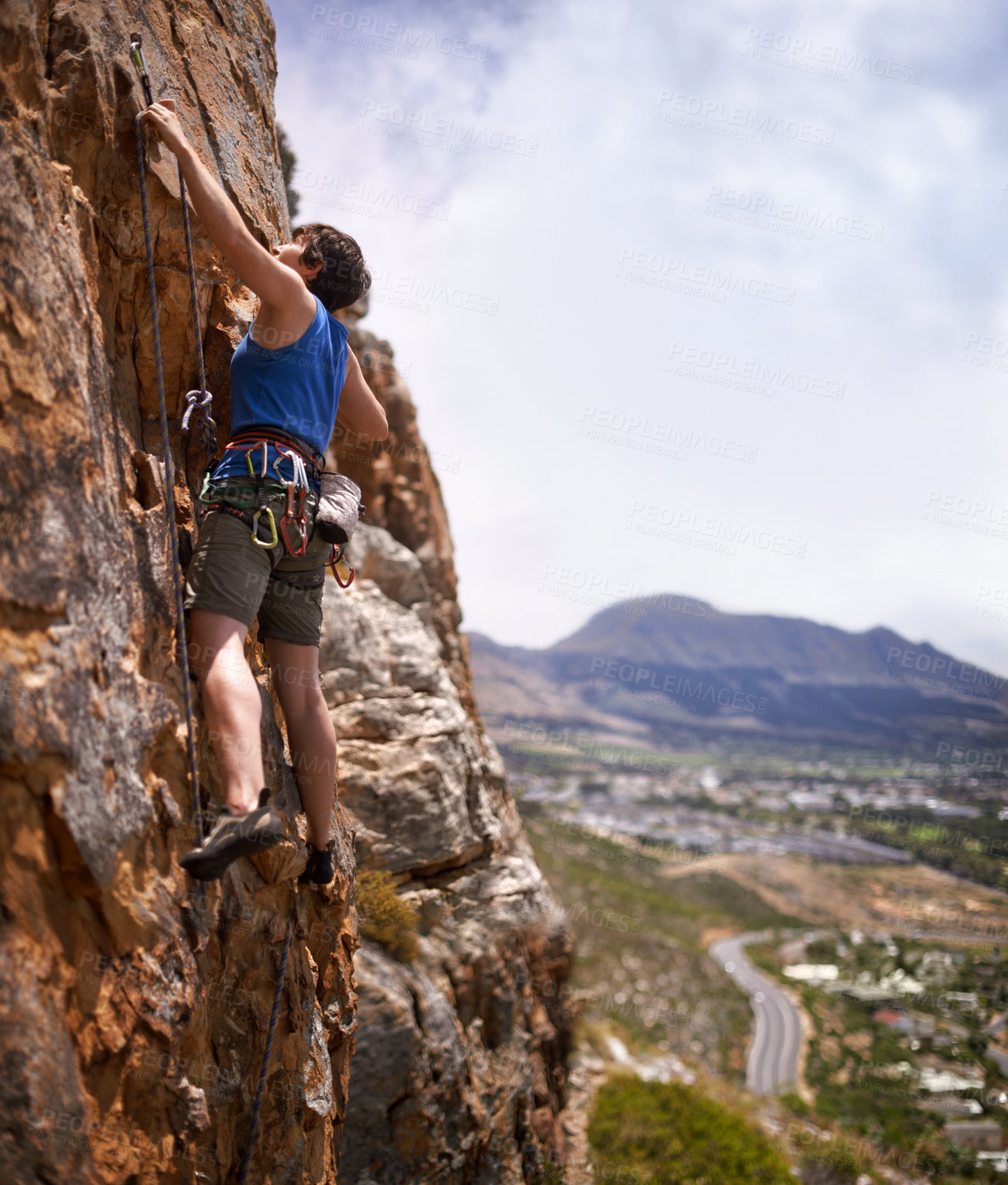 Buy stock photo Shot of a young woman clipping in a bolt while rock climbing