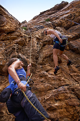 Buy stock photo Two female rock climbers scaling a rock face