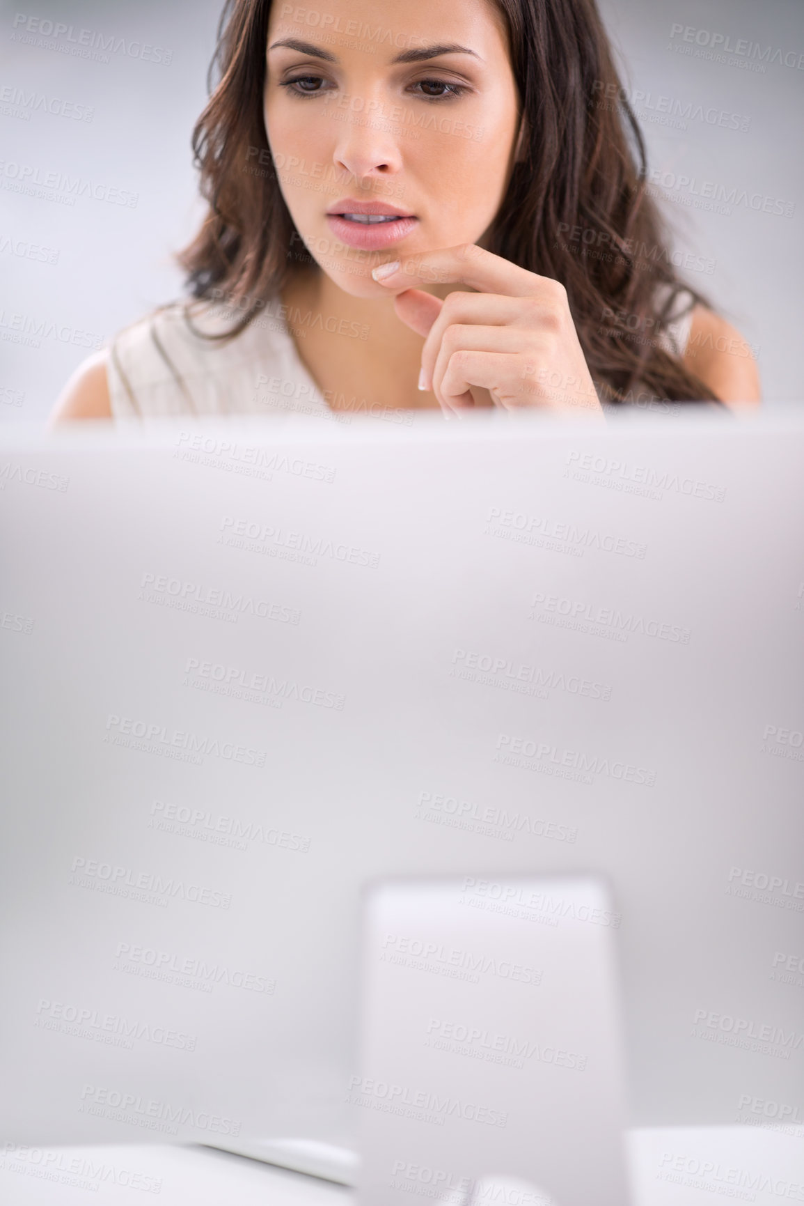 Buy stock photo Young, serious and thinking businesswoman on a computer working on solving a business problem. Professional caucasian corporate female sitting and doing research for a company project on a modern pc