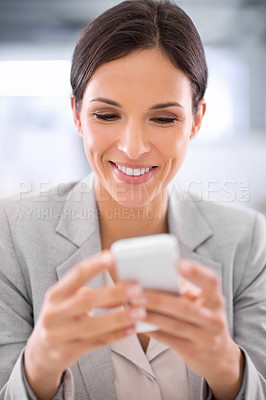 Buy stock photo Shot of a woman using a cellphone while sitting at a desk in an office