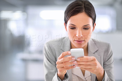Buy stock photo Young woman browsing social media on a phone at work in a modern office. Serious female interested and curious about fake news or stories. Lady reading updates on the internet while on a break 