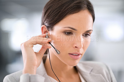 Buy stock photo Confident, serious and listening call center agent busy on a call, helping and assisting remotely with customer care and IT support. Young woman answering and talking with a headset in her office