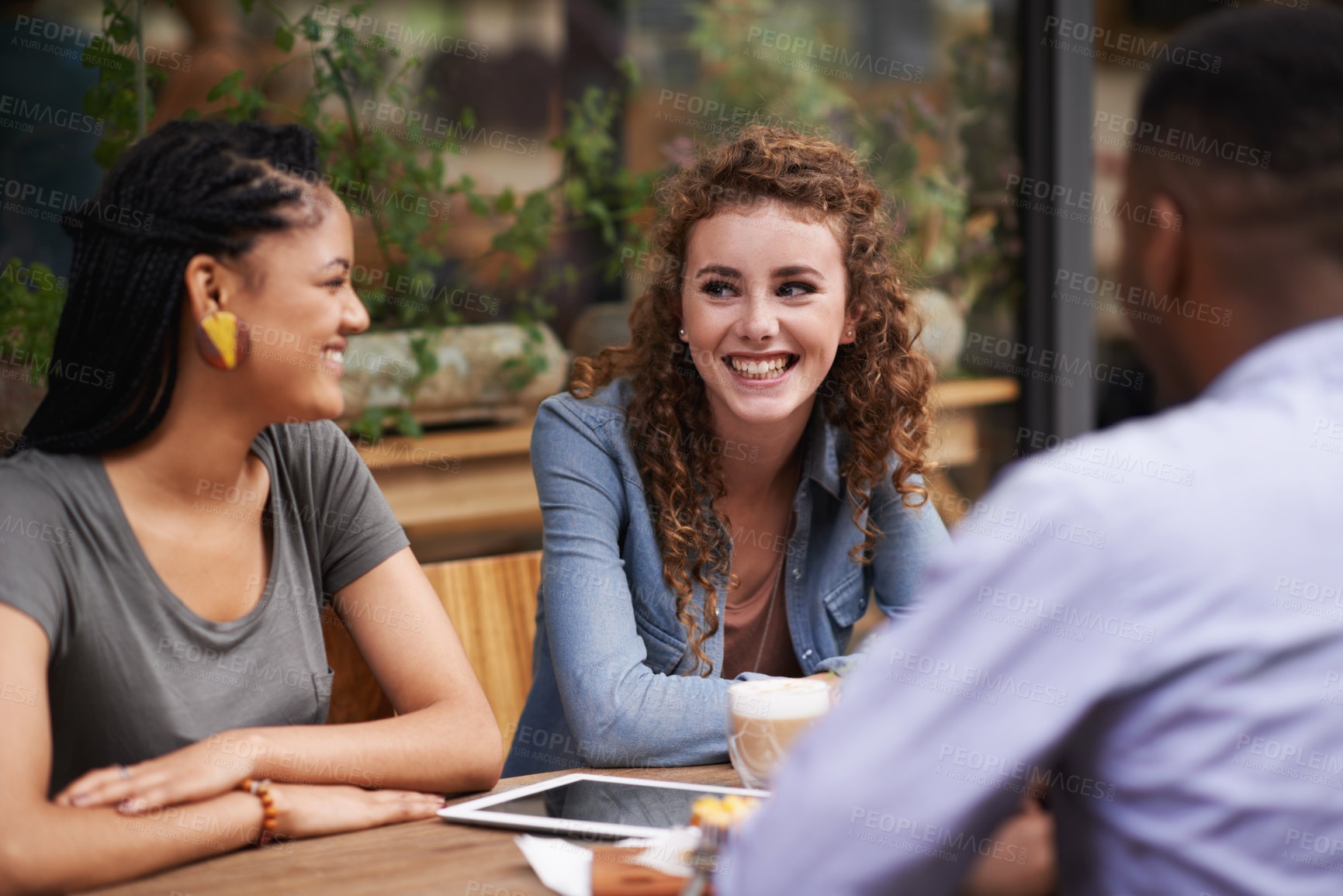 Buy stock photo A group of young friends sitting outside at a sidewalk cafe