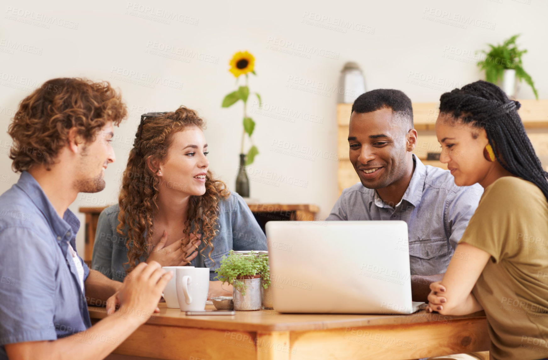 Buy stock photo A group of friends sitting together in a coffee shop with a laptop