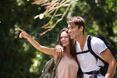 Buy stock photo Couple, point and smile for hiking in jungle with sign for thinking, holiday and happy on path. Man, woman and bag for trekking, direction and search in rainforest with ideas at location in Colombia