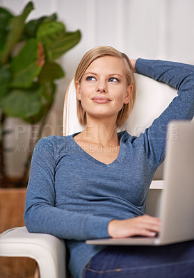 Buy stock photo Shot of a beautiful woman sitting on a couch using a laptop