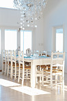White interior with dining table and chairs and chandelier