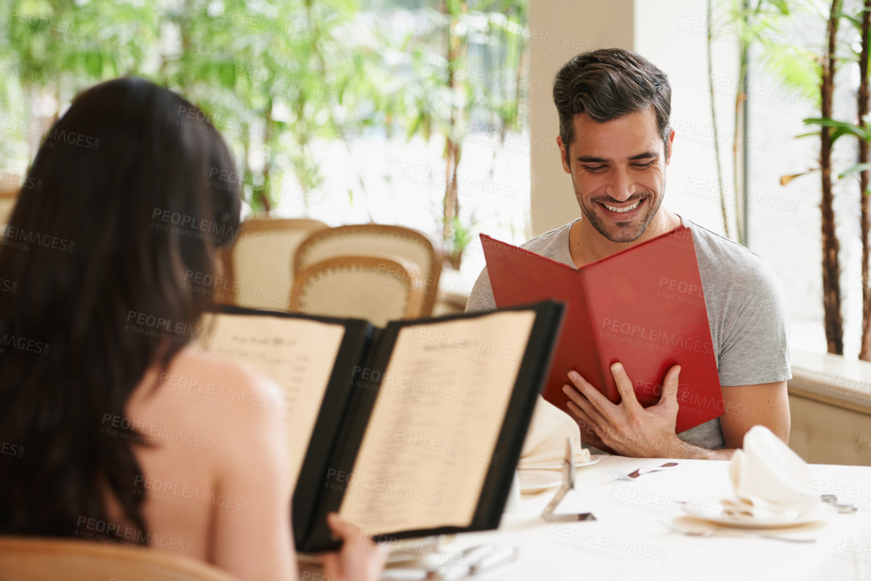 Buy stock photo Happy couple, date and reading menu at restaurant for fine dining, romance or ordering food together. Young man and woman looking at brochure with smile for meal, dinner or decision in eating choice