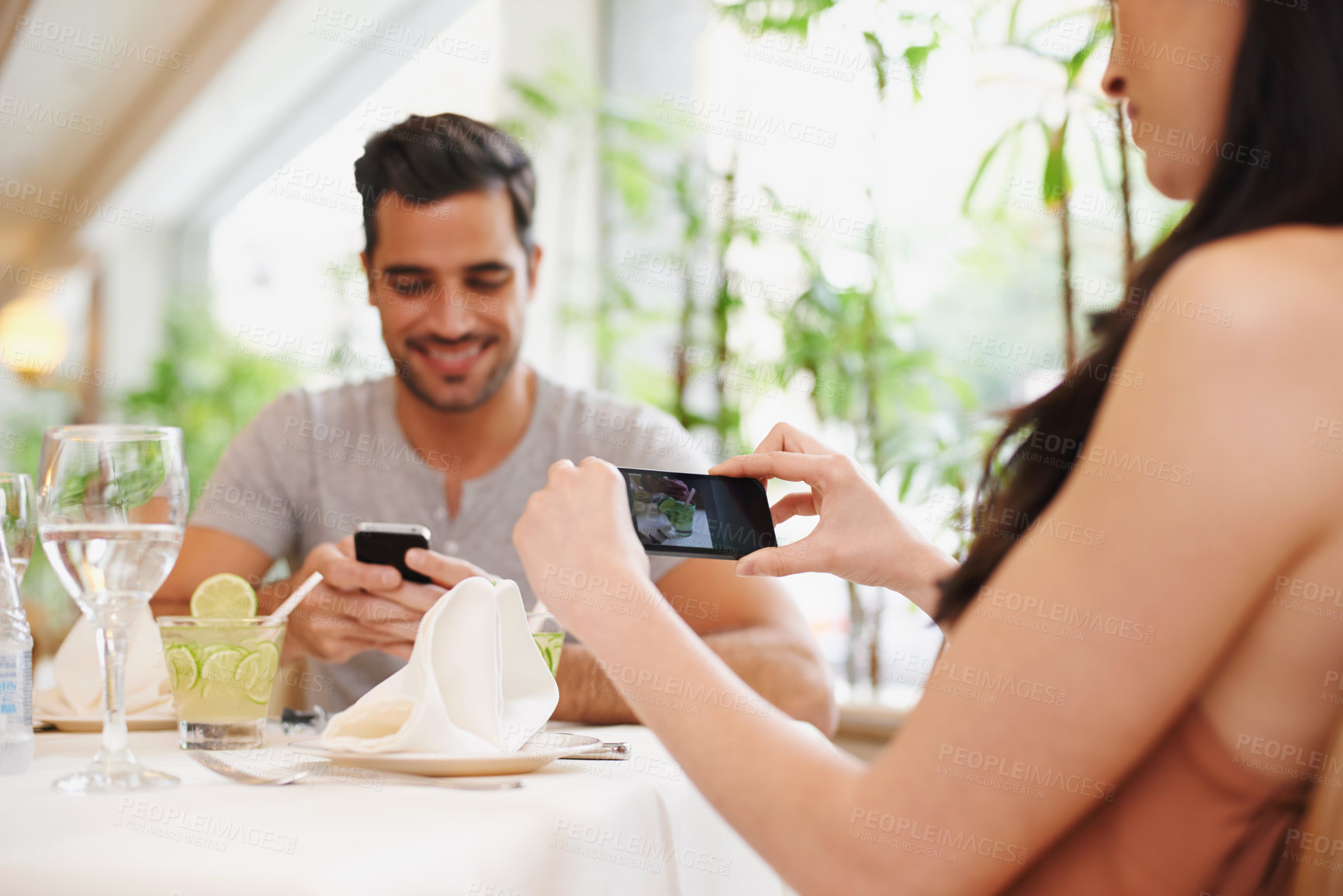 Buy stock photo A woman taking a picture while dining out with her partner at a restaurant