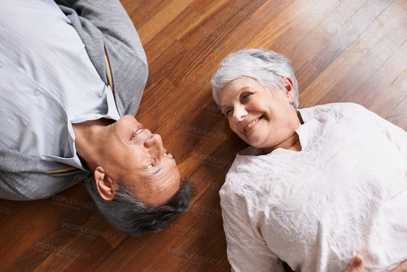 Buy stock photo Smile, senior or happy couple on floor to relax in home living room for bonding or support in retirement. Above, old people or man lying down by an elderly woman for trust, peace or care in marriage