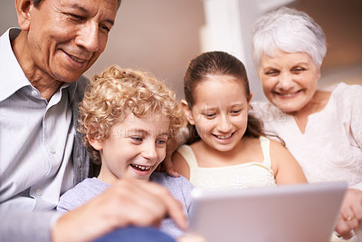 Buy stock photo A shot of two kids and their grandparents using a digital tablet while sitting on the sofa