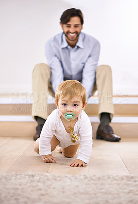Buy stock photo A handsome young father watching his baby boy crawl