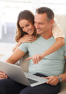 Buy stock photo Happy couple, computer and pointing on home internet for online planning, website and to check application together. Hug, love and mature partner, woman or people on sofa reading on laptop technology
