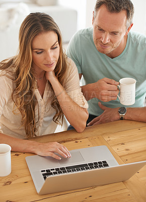 Buy stock photo Laptop, home and couple reading online, scroll on internet together and check website or application for information. Mature partner, woman or people on computer or pc with coffee or tea at table