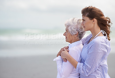 Buy stock photo Shot of a beautiful young woman and her senior mother on the beach
