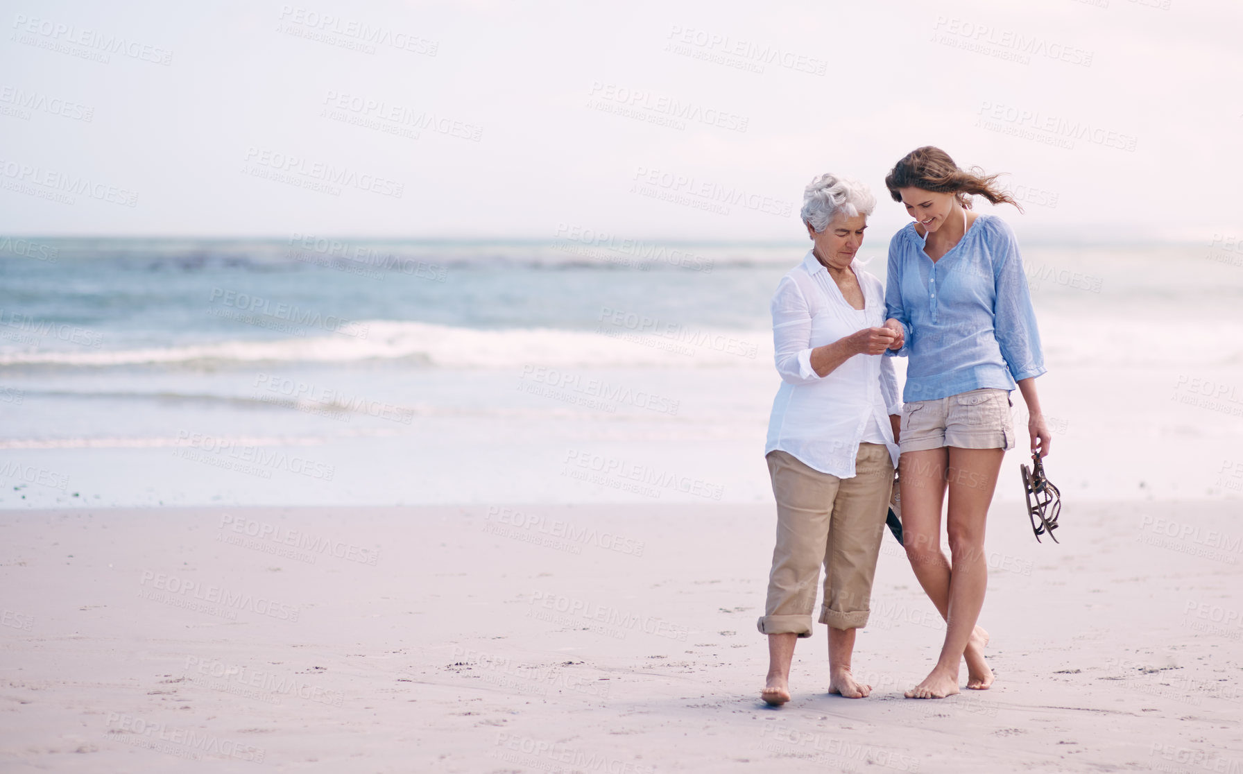 Buy stock photo Shot of a senior mother and her adult daughter exploring the beach