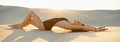 Buy stock photo Shot of a beautiful young woman in swimwear lying on the sand at sunset