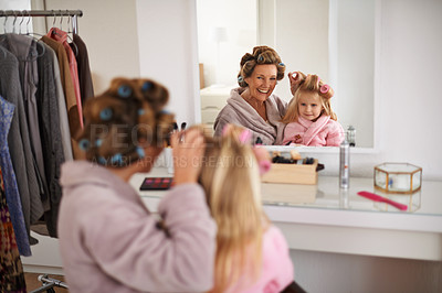 Buy stock photo Mother, child and playing with hair in mirror for beauty, care and helping or getting ready. Excited mom, family and daughter or kid with rollers for hairstyle, fashion and bonding together at home
