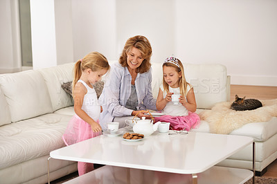 Buy stock photo Grandmother, kids and talking with tea party in living room for bonding, playing and breakfast or brunch at home. Happy senior woman, family and girl or children with drink and princess game for fun