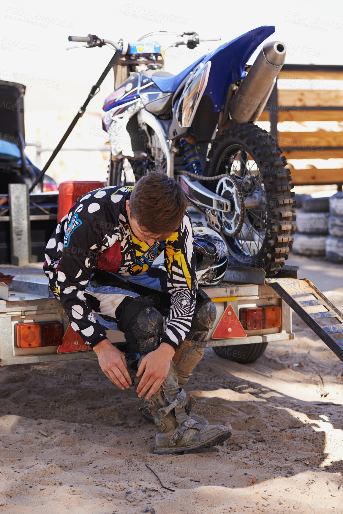 Buy stock photo Motorbike, race and sports with man getting ready for off road adrenaline, competition or training outdoor. Boots, adventure and dirtbike hobby with person in gear on trailer for performance