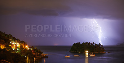 Buy stock photo Shot of a dramatic thunderstorm over sea and land