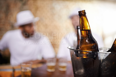 Buy stock photo Beer bottles, alcohol and beverages with men by bar, pub or nightclub for drinking, socializing or partying. Ciders, ice bucket or glasses on counter at tavern, lounge or restaurant for entertainment