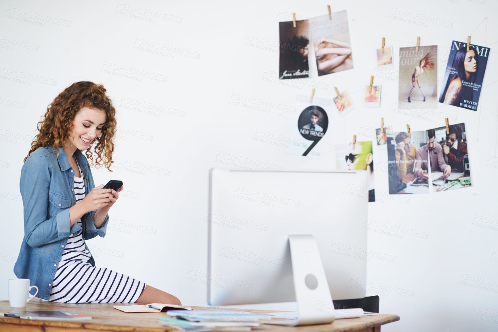 Buy stock photo Shot of a young woman using a cellphone while sitting on her desk in an office