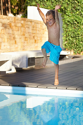 Buy stock photo An excited young boy jumping into a swimming pool