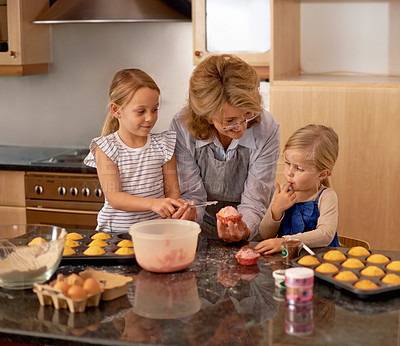 Buy stock photo Two little girls baking cupcakes with the help of their grandmother at home