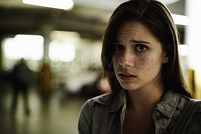 Buy stock photo A terrified young woman in an underground parking garage being followed by a sinister man