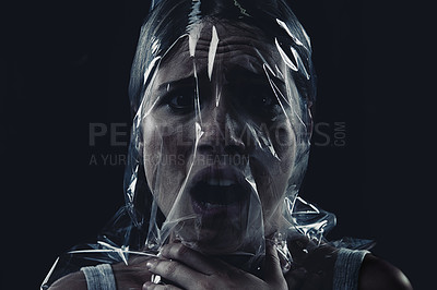 Buy stock photo Scary, face and woman with plastic or bag in horror, drama or death in dark background of studio. Suffocating, murder and girl with fear from crime, victim and trapped in trash, garbage or pollution